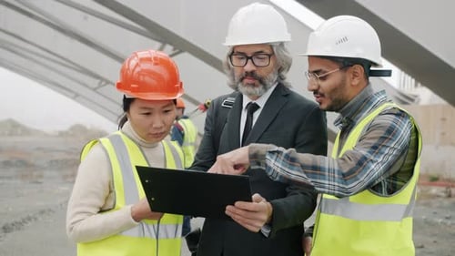 Team of Construction Workers Look at Clipboard