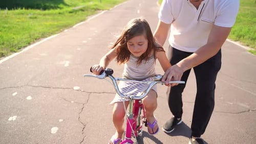 Un père heureux se réjouit que sa fille ait appris à faire du vélo