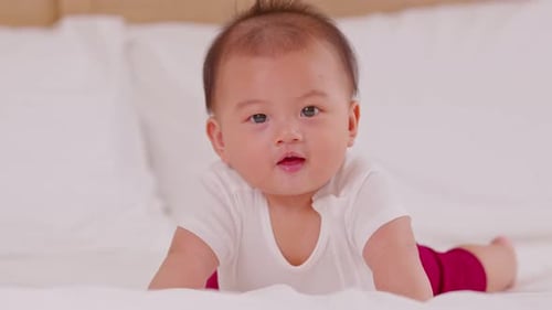 Infant Lying on Stomach on a White Bed