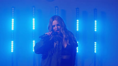 Woman Singing On Stage Under Blue Lights