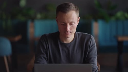Handsome Freelancer Businessman in Glasses Diligently Working on Laptop in Cafe