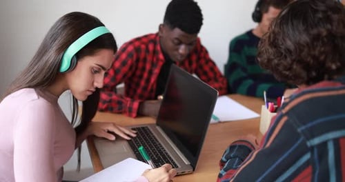 Multiracial students reading books and using laptop while studying together - School concept