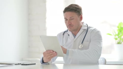 Male Doctor using Tablet while Sitting in Office