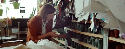 Mujer tomando lo último de la estantería en un taller de fabricación de zapatos