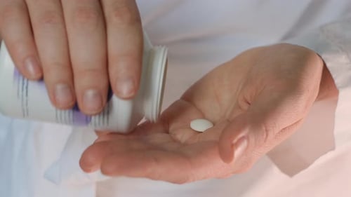 Hand Ärztin legt sich hin und legt weiße Pillen in die Hand