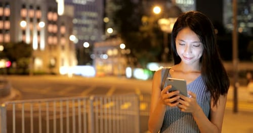 Woman using mobile phone in the city at night