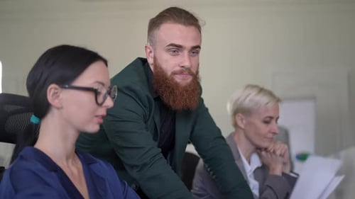 Confident Bearded Caucasian Man in Formal Suit Talking with Female Colleagues Sitting at Table