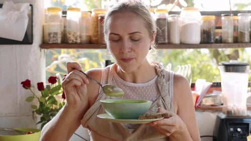 Woman Tastes Soup in Bright Kitchen