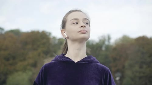 Front View of Confident Positive Female Jogger Running Outdoors on Cloudy Morning
