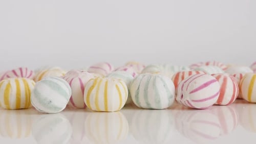 Colorful striped bonbons on white 4K tilting footage