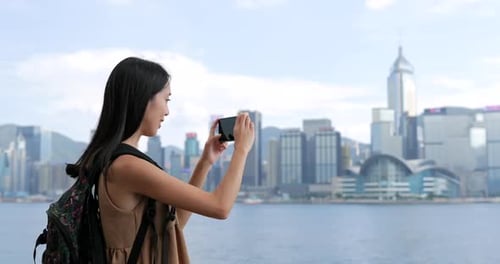 Young Woman taking photo with cellphone in Hong Kong Victoria harbor