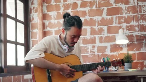 Young Adult Playing Acoustic Guitar Indoors