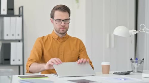 Junger Mann schließt Laptop und geht weg