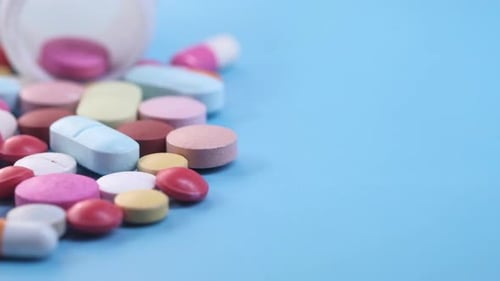 Close Up of Colorful Pills Spilling on Blue Background