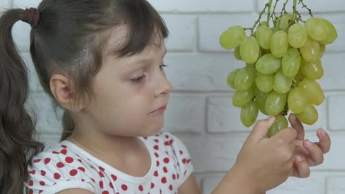The kid eats grapes.