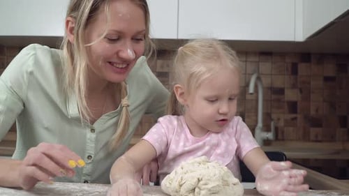 Mother and Daughter Kneading Dough in the Kitchen