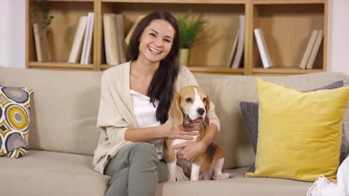 Woman Pets Dog on a Couch