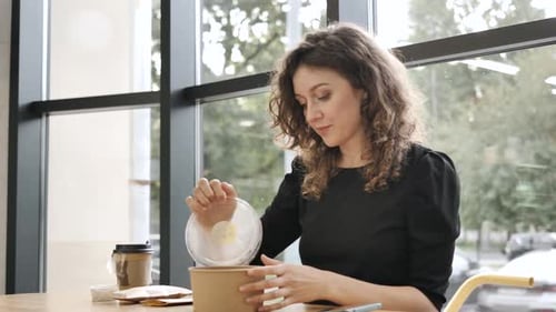 Lady Opens Paper Container with Dish Takes Packet in Cafe