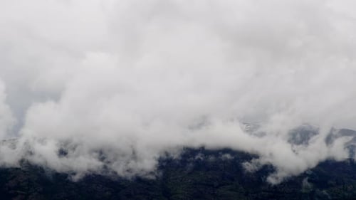 Gruppe großer weißer Wolken, die den Berggipfel bedecken