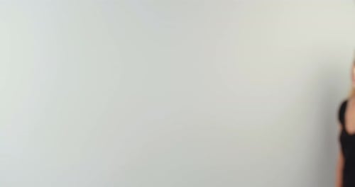 Young blond woman walking up to the camera and smiling on white studio background