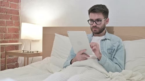 Man Using Tablet While Relaxing in Bed