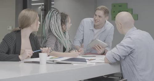 Four Cheerful Young Colleagues Talking and Giving Highfive in Office