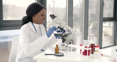 Female Scientist Using Microscope in Bright Lab