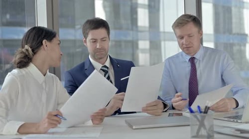 Executive Business People Having Arguments on Documents While Sitting on Office Table