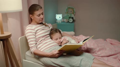 Woman Reads Bedtime Story to Child in Bed