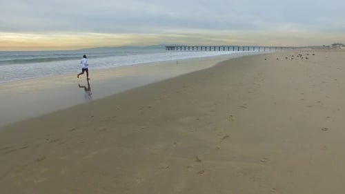Aerial shot of young man running on the beach.