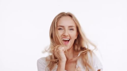 Joven hermosa chica rubia caucásica bailando activamente, regocijándose, sonriendo, gesticulando en blanco