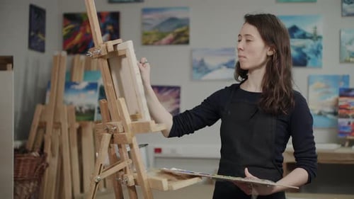 Young Brunette Woman Is Creating Picture in Artistic Workshop Standing