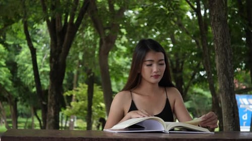 Woman Reads a Large Book Outdoors