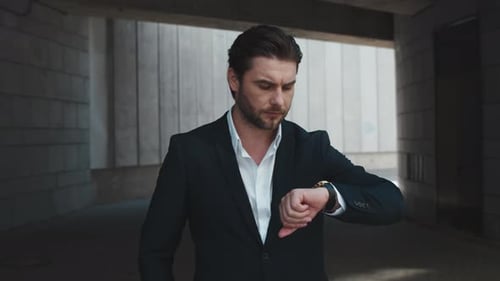 Focused Businessman Checking Time Outside Near Concrete Wall