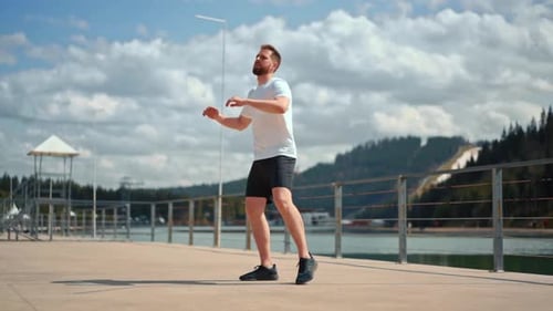 Man Warming Up on Lakeside Pier on Sunny Day