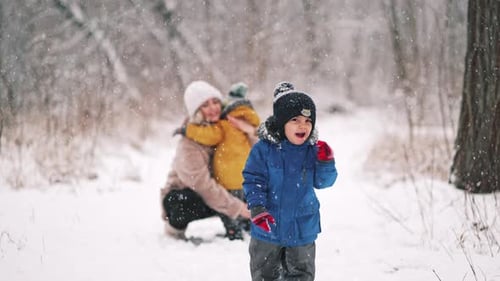 Erstaunliche Aussicht, wie Kleinkind Junge mit Lächeln im Winterwald zur Kamera rennt