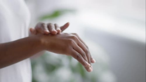 Woman Applies Lotion to Hands for Self Care