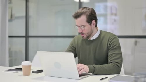 Young Businessman Coughing While Using Laptop in Office
