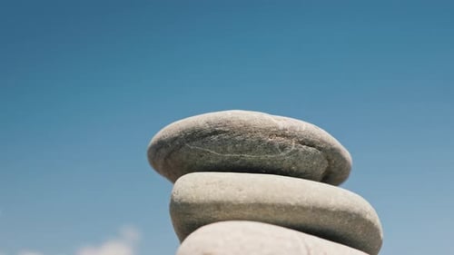 El hombre construye una pirámide de guijarros contra el cielo azul