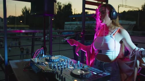 Woman DJ Performing Outdoors With Phone in Hand