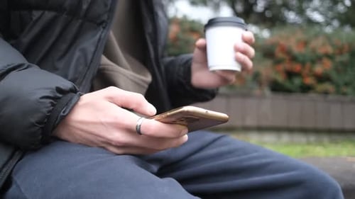Young Adult Male Uses Mobile Phone Outdoors