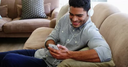 Man Listening Music on Couch with Headphones