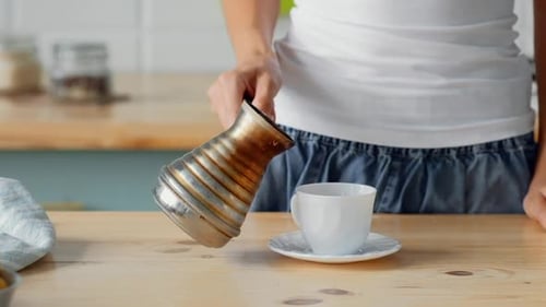 Person Pouring Fresh Coffee in Kitchen