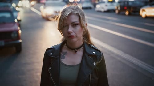 Model Hipster in Black Leather Jacket and Choker is Posing By a Road of City Street with Busy