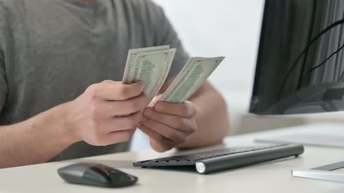 Hands of Man Counting Dollars Near Desktop Close Up