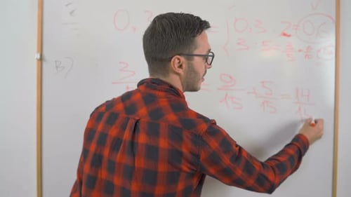 Close Shot of Young Man Math Teacher with Red Shirt and Glasses Writing Complex Math Equations on