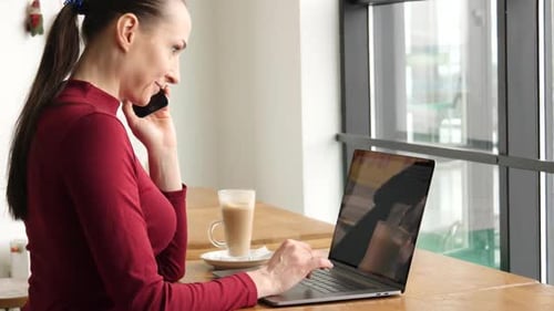 Woman Using Smartphone in Cafe Drinking Coffee Smiling and Calling on Mobile Phone.