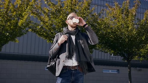 Young caucasian businessman is drinking coffee in the modern center city