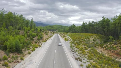 Die Drohne fliegt dem Auto hinterher, das die Straße entlang durch die Berge und den Wald in Manavgat fährt
