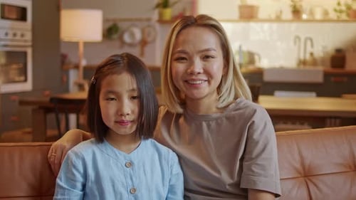 Woman and Girl Smiling Together on Couch at Home